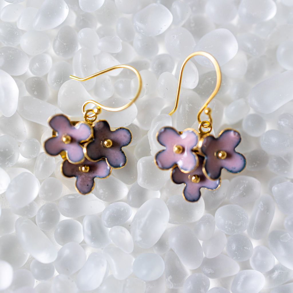 Pair of floral earrings with gold accents on a textured white surface