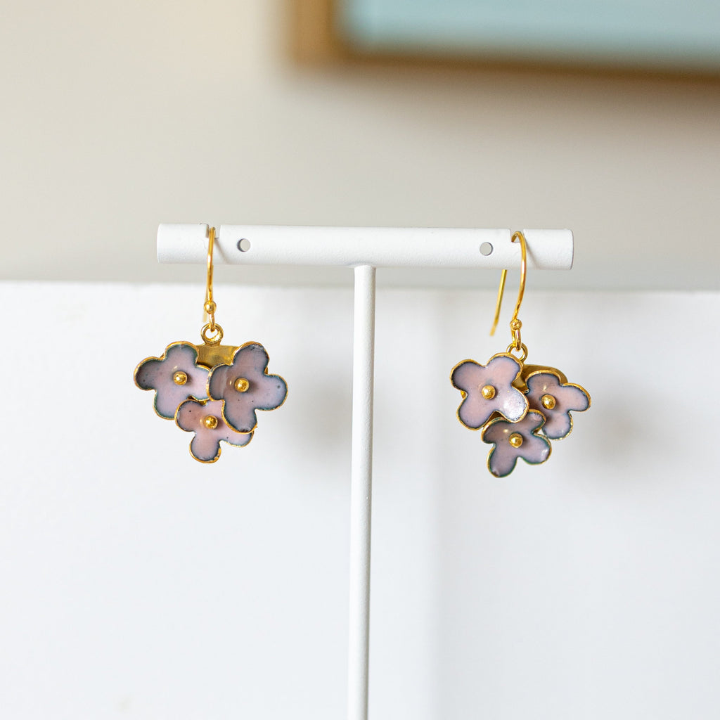Flower-shaped earrings on a white stand against a neutral background