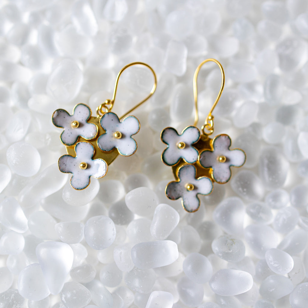 Floral earrings with gold accents on a textured white background