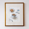 Framed artwork of coffee cups on a white wall