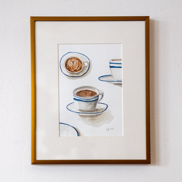 Framed artwork of coffee cups on a white wall