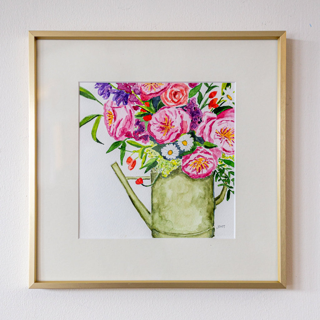 Framed artwork of a watering can with flowers on a white wall