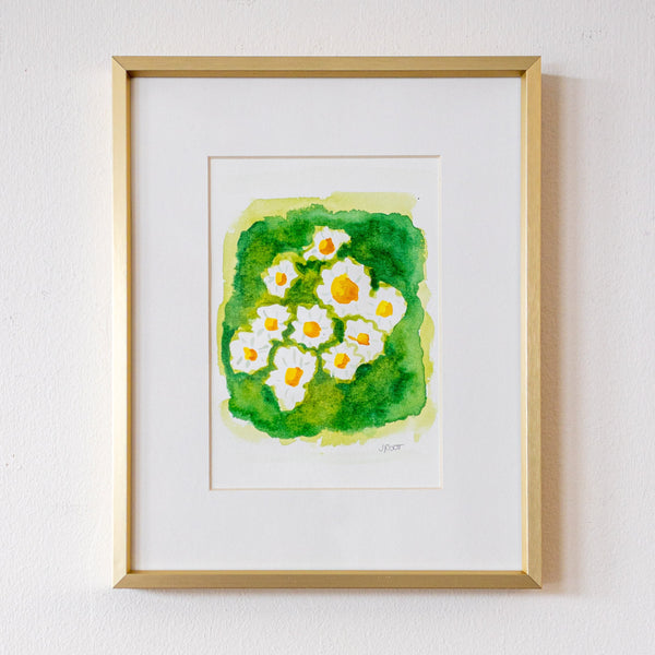 Framed artwork of white flowers with green leaves on a white wall