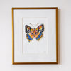 Framed artwork of a colorful butterfly on a white wall