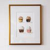 Framed artwork of four cupcakes on a white wall