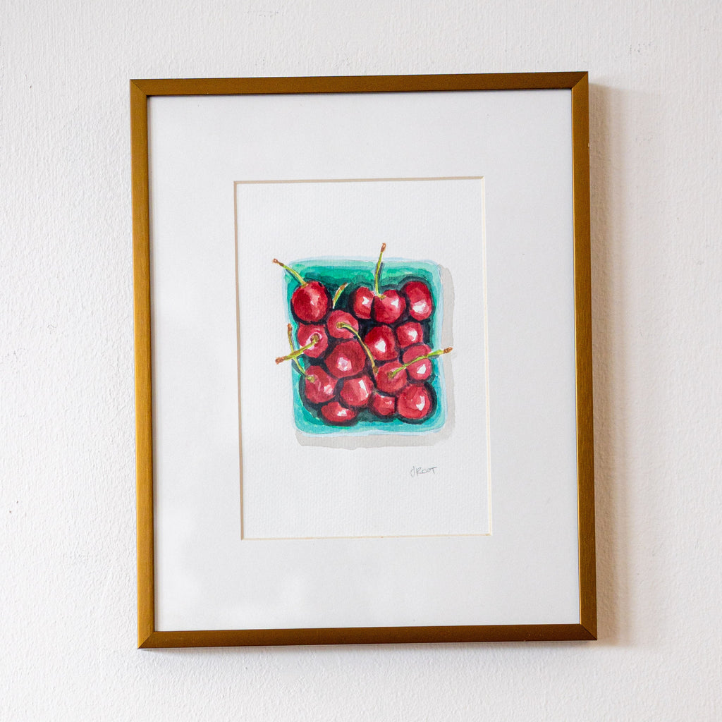 Framed artwork of cherries on a white wall
