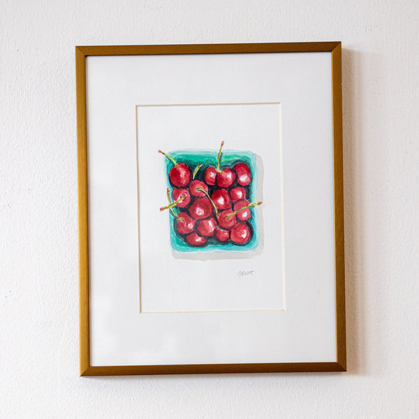 Framed artwork of cherries on a white wall