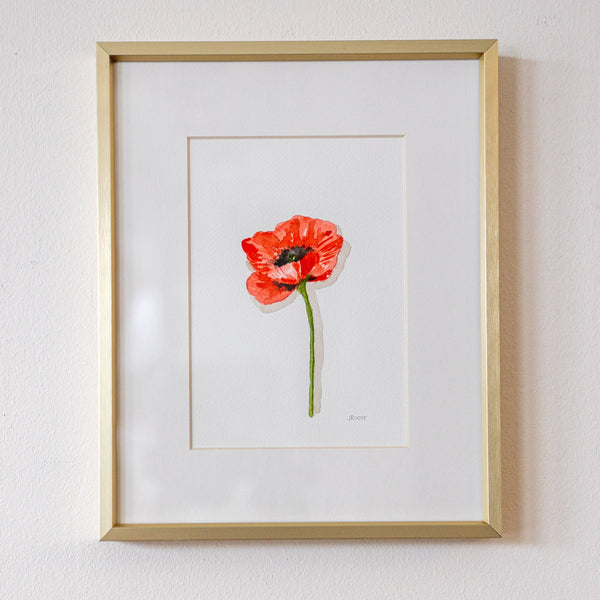 Framed artwork of a red flower on a white wall