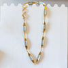 Gold necklace on a display stand with a card in the background