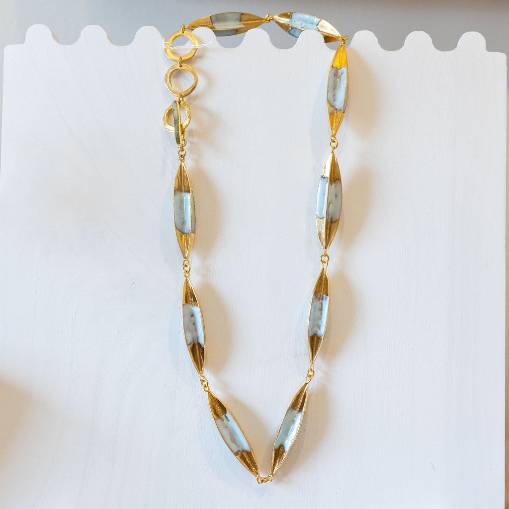 Gold necklace on a display stand with a card in the background