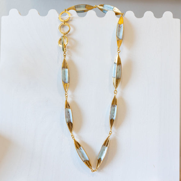 Gold necklace on a display stand with a card in the background