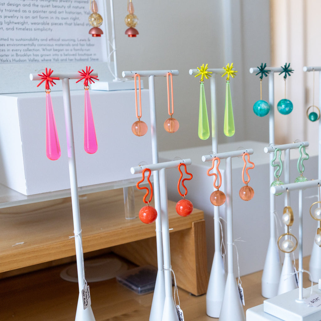 Collection of colorful earrings on display stands in a store setting.