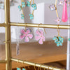Gold earring rack with colorful floral earrings on a blurred background