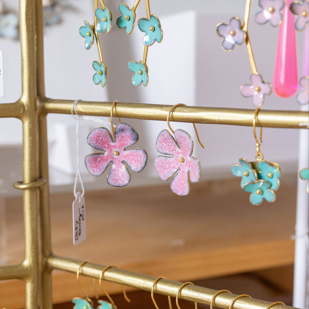 Gold earring rack with colorful floral earrings on a blurred background