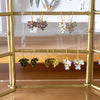 Gold earring rack with various earrings on a wooden surface
