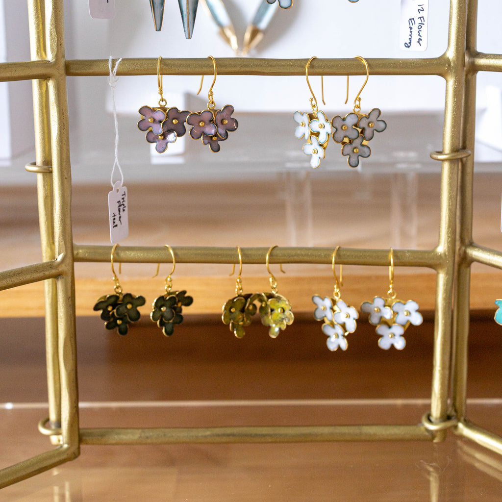 Gold earring rack with various earrings on a wooden surface