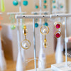 Earring display stands with various earrings on a wooden surface.