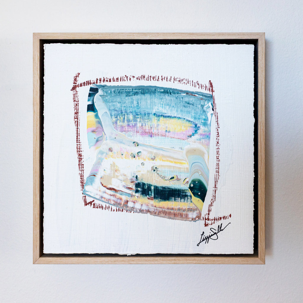 Framed abstract artwork with a signature on a white wall
