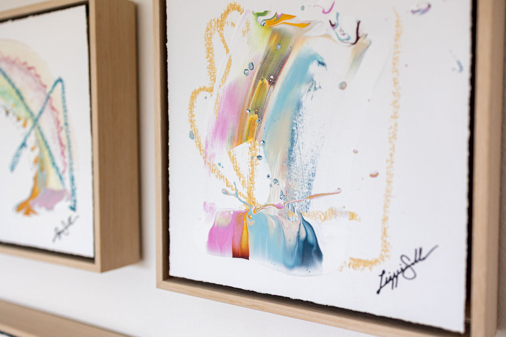 Framed abstract art pieces with colorful brushstrokes on a white wall.