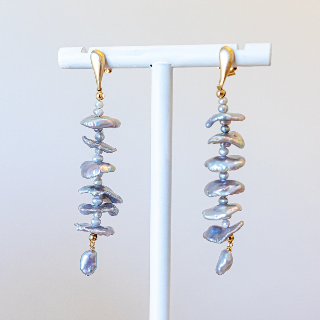 Pair of spiral-shaped earrings on a white stand against a light background
