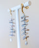 Pearl and gold earrings on a white stand with a light background