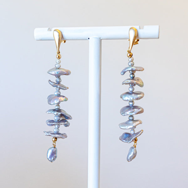 Pair of spiral-shaped earrings on a white stand against a light background