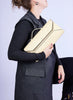 Person holding a yellow clutch bag against a light purple background