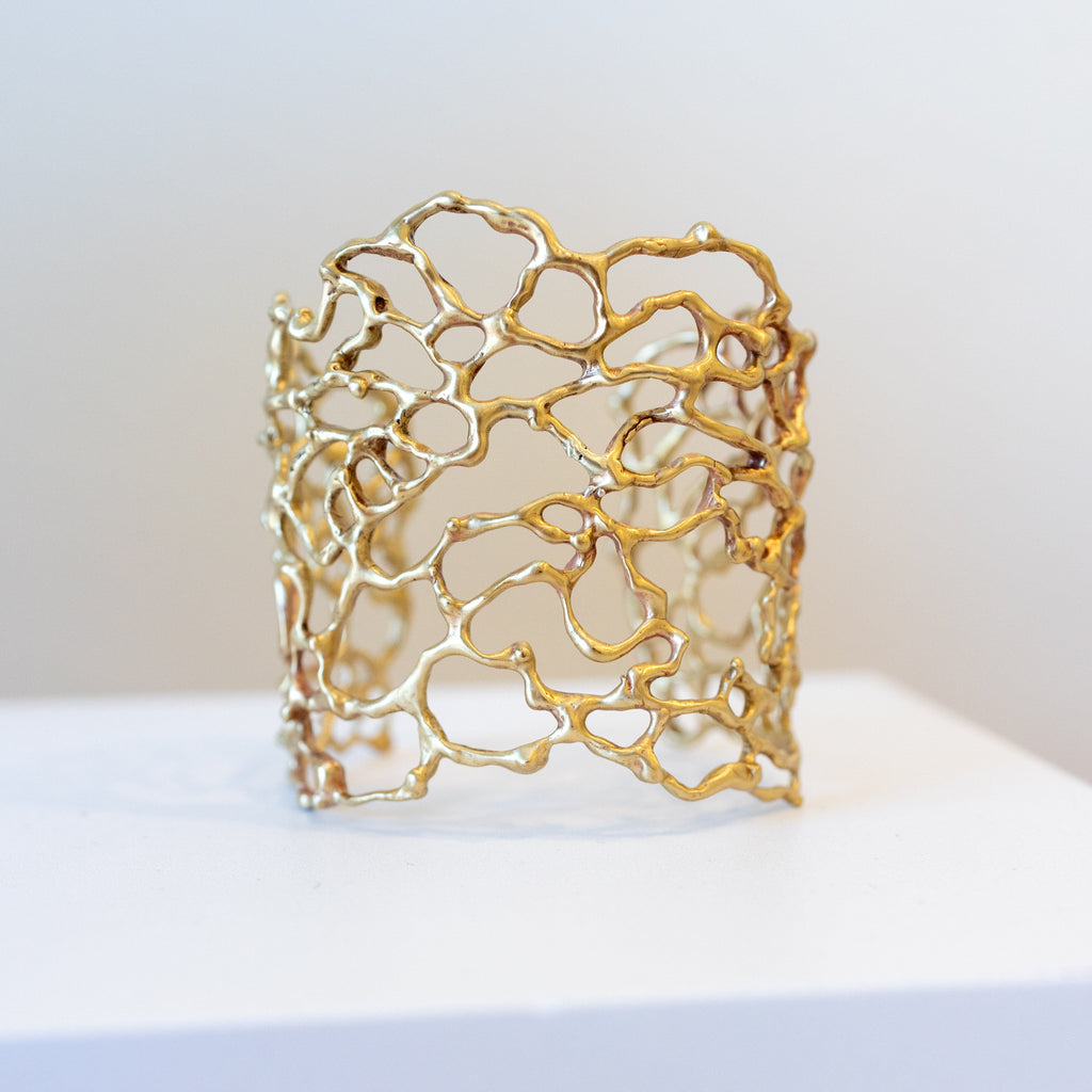 bronze cuff bracelet on a white surface with a light gray background