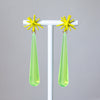 Pair of earrings with yellow star-shaped tops and green teardrop-shaped bottoms on a gray background.