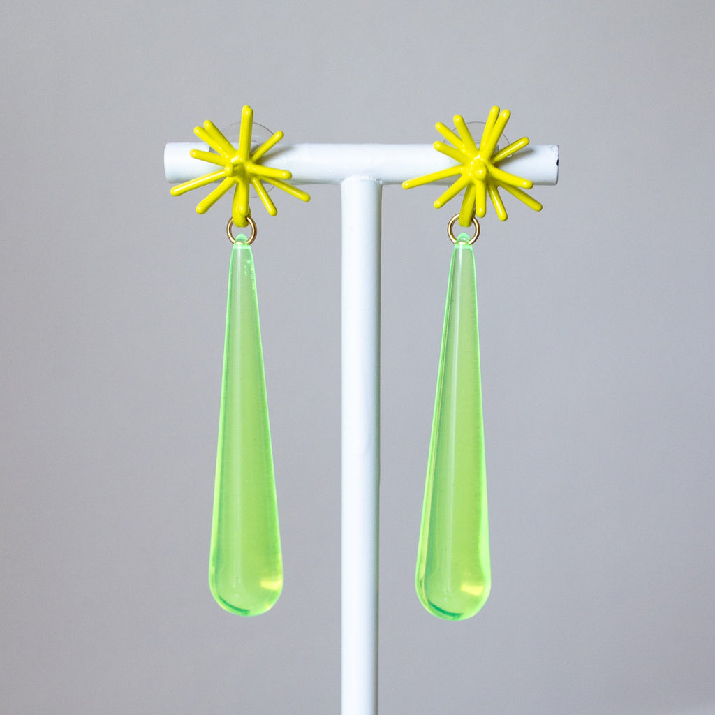 Pair of earrings with yellow star-shaped tops and green teardrop-shaped bottoms on a gray background.