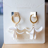 Gold hoop earrings on a white card with 'Noonday' branding.