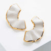 Pair of gold and white earrings on a light gray background