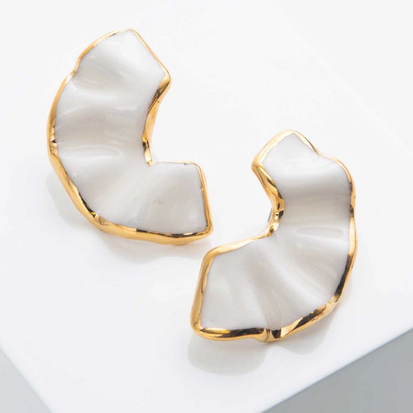 Pair of gold and white earrings on a light gray background