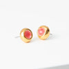Gold stud earrings with coral accent on a white background