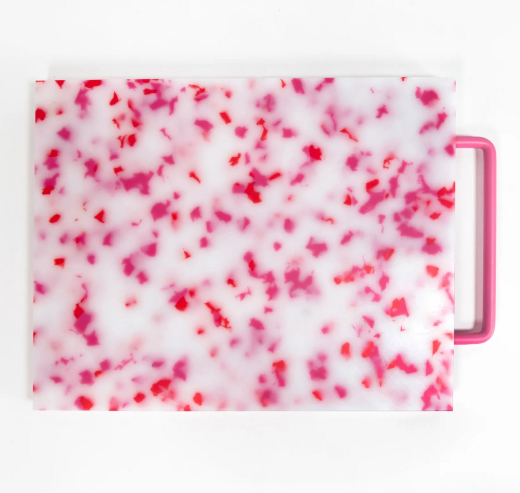 Pink and white marbled patterned cutting board with a handle on a white background