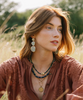 Woman with earrings and necklaces sitting in a field