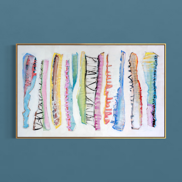 A framed abstract canvas print featuring vertical multicolored brushstrokes on a white background, hung on a solid slate blue wall.
