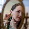Woman adjusting earrings in front of an ornate mirror