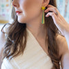 Woman wearing a white dress and green earrings with a blurred background