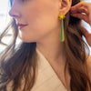 Woman wearing a green and yellow earring, with a blurred background