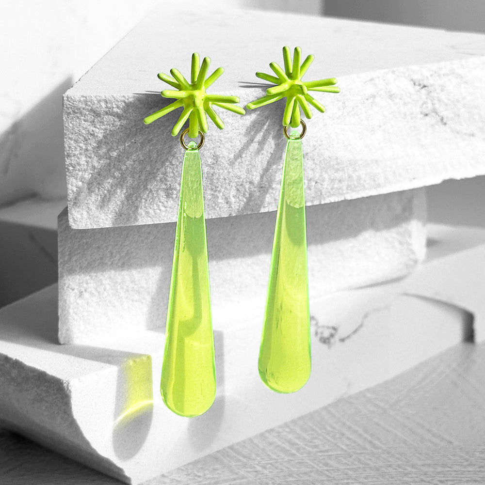 Pair of lime green earrings with star-like top and teardrop shape on a white surface.