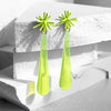 Pair of lime green earrings with star-like top and teardrop shape on a white surface.
