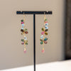Multicolored beaded earrings on a black display stand against a neutral background