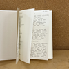 Open book with handwritten text on a cork background