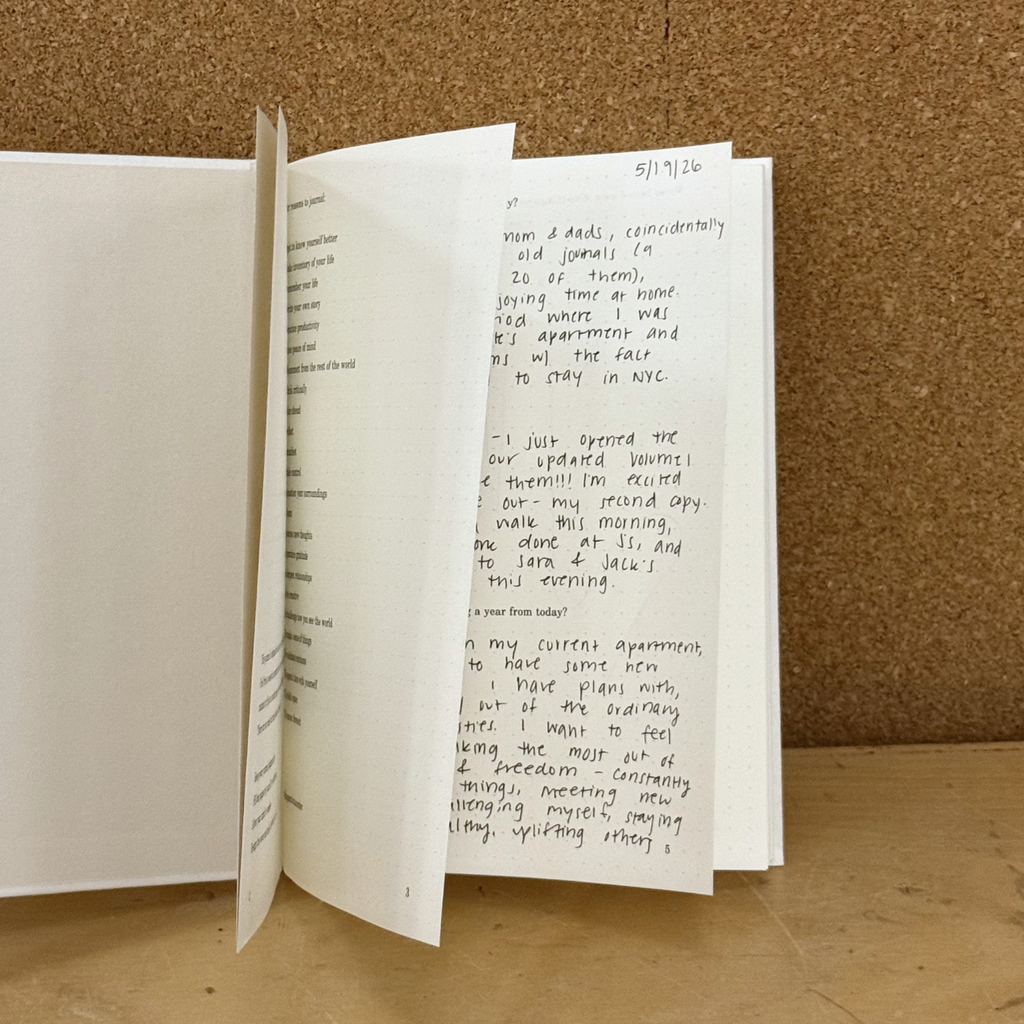 Open book with handwritten text on a cork background