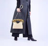 Person wearing a long dark coat holding a yellow handbag with an architectural strap on a white background