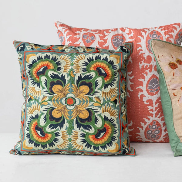 Three decorative pillows with intricate patterns on a white background