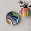 Colorful mug and coaster set on a textured surface