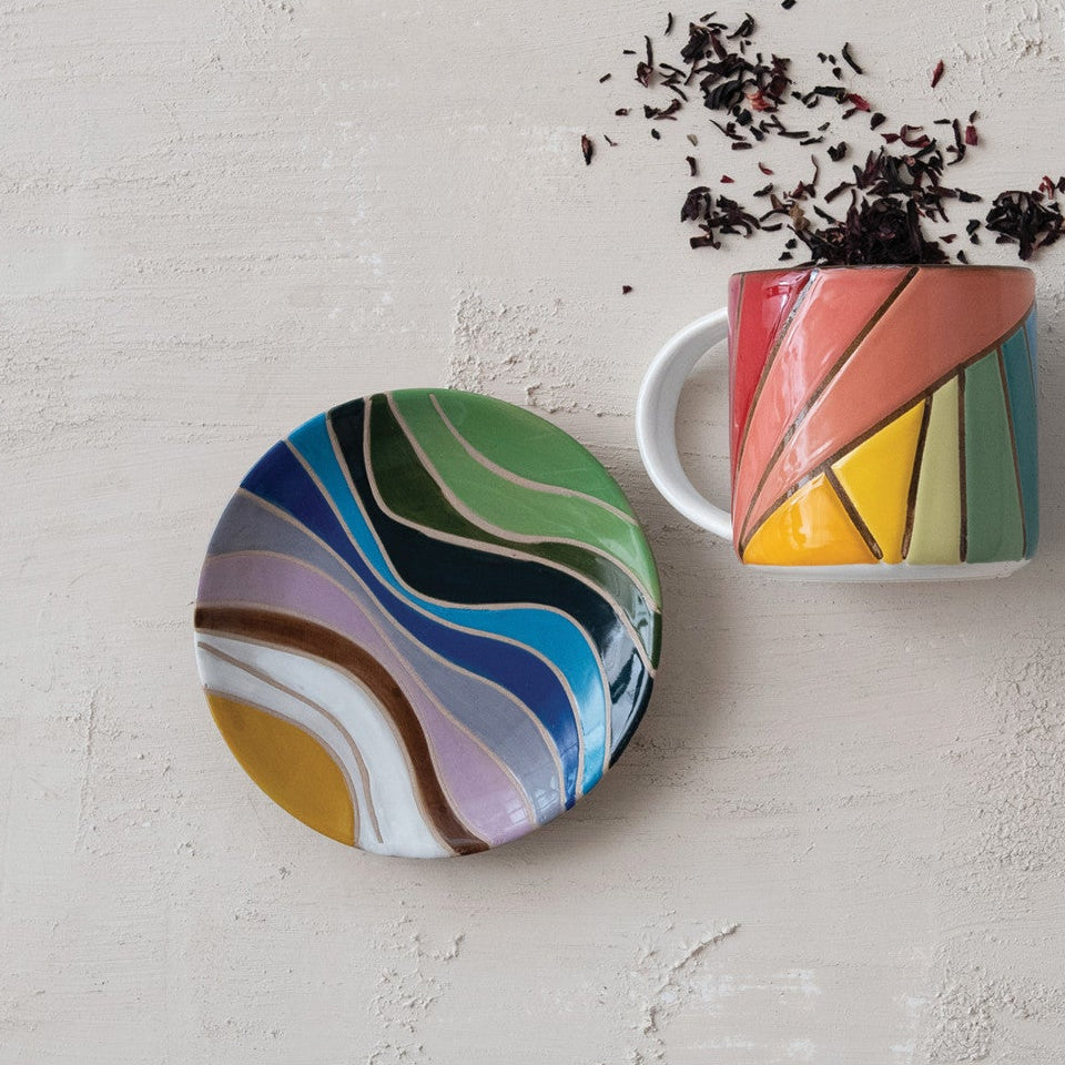 Colorful mug and coaster set on a textured surface