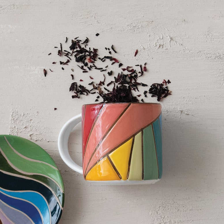 Colorful mug and coaster set on a textured surface